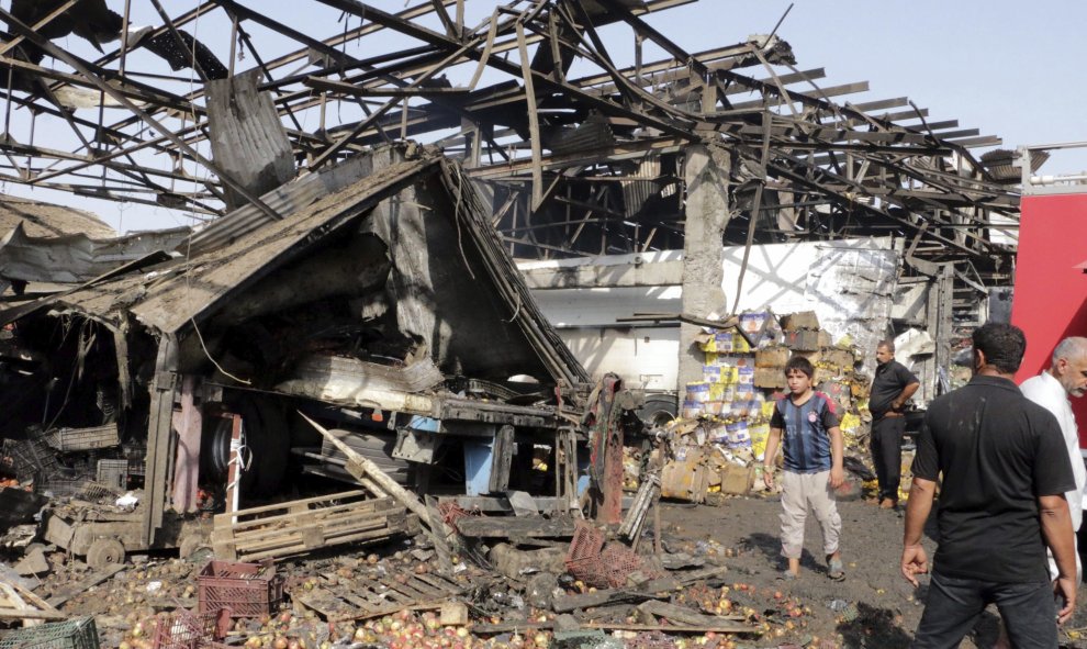 Varias personas caminan por el lugar donde se ha producido un atentado en un mercado en Bagdad (Irak) reivindicado por el grupo terrorista Estado Islámico. EFE/Ahmed Ali