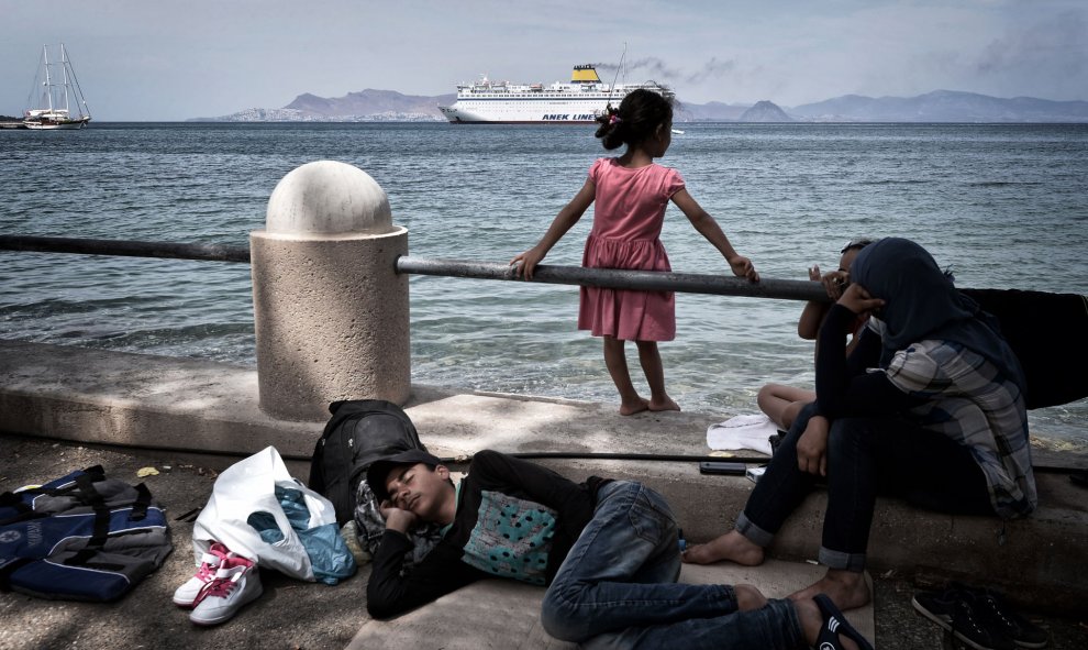 Inmigrantes sirios ven la llegada del ferry de Eleftherios Venizelos desde el campamento improvisado en la costa de la isla griega de la isla de Cos , el 14 de agosto de 2015. AFP PHOTO / LOUISA GOULIAMAKI