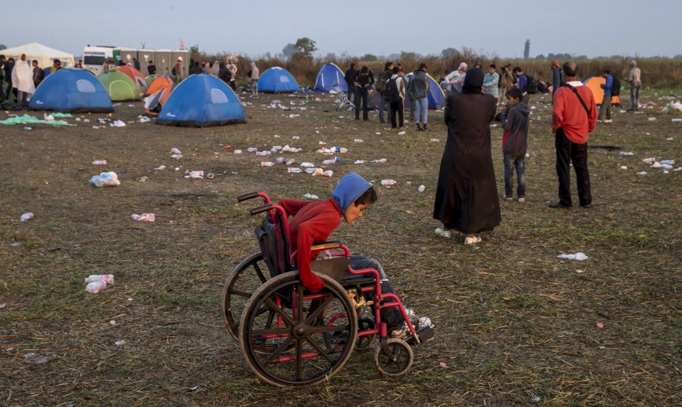 Un niño juega con una silla de ruedas en un campo cerca del pueblo de Röszke, Hungría, 5 de septiembre de 2015. REUTERS / Marko Djurica