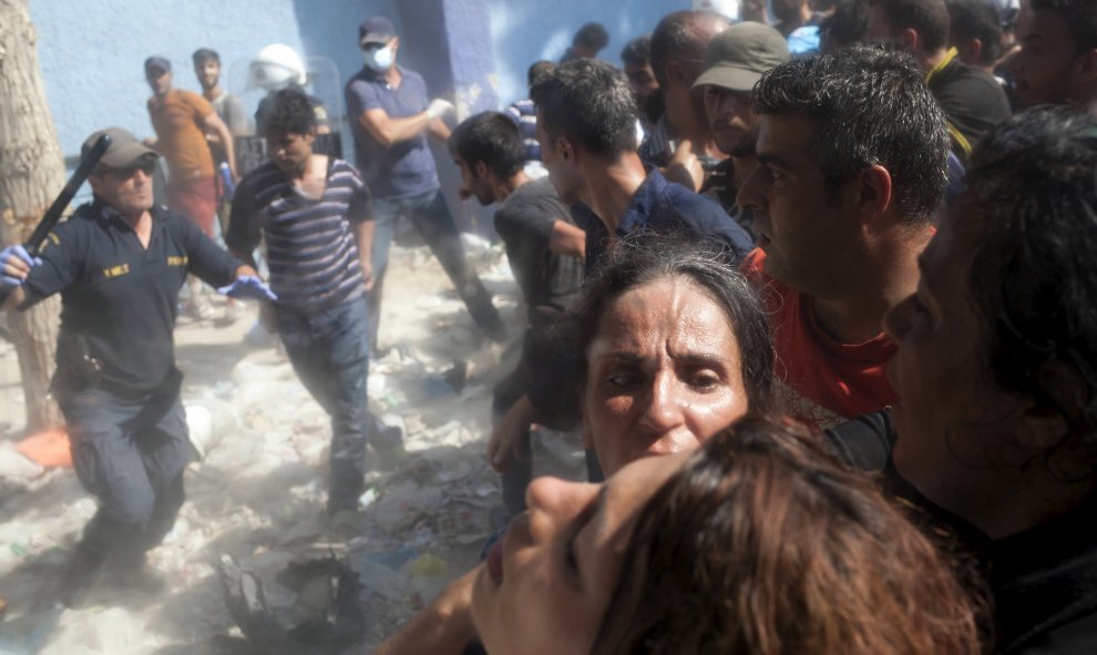 Un policía corre con una porra para hacer retroceder a los refugiados y los inmigrantes en la espera del proceso de registro en el puerto de Mitilene, en la isla griega de Lesbos, 5 de septiembre de 2015. REUTERS / Dimitris Michalakis