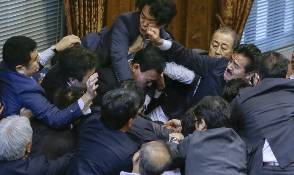 El miembro de la oposición Yukihiro Knishi (c) recibe un puñetazo del consejero del gobernante Partido Liberal Demócrata (PDL) Masahisa Sato (d) mientras se enzarzan en una pelea tras la aprobación de la polémica reforma militar en la Cámara Alta de la Di