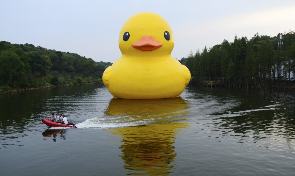 Trabajadores viajan en un barco de alta velocidad y pasan por delante de pato de goma inflable colocado por el artista holandés Florentijn Hofman, en un lago en un jardín botánico en Changsha, provincia de Hunan , China. REUTERS/Stringer