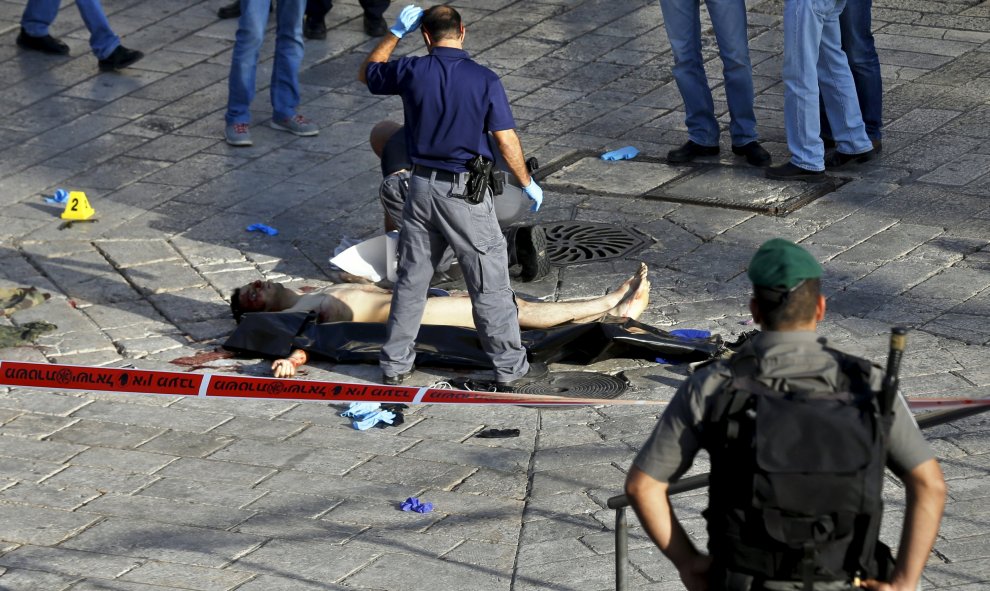 Policías israelíes comprueban el cuerpo de un hombre palestino que intentó apuñalar a la policía y fue abatido a tiros según un portavoz de la policía israelí, en una entrada a la amurallada Ciudad Vieja de Jerusalén, 14 de octubre de 2015. REUTERS / Baz