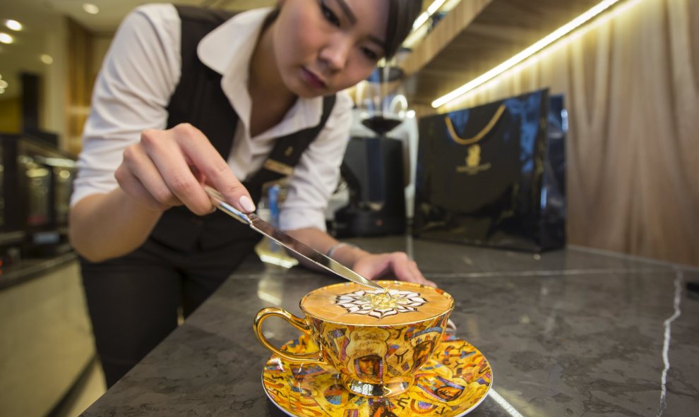 Una empleada del hotel Ritz-Carlton de  Almatý, en Kazajistán, sirve un capuchino con oro comestible al precio de 9,5 euros. / SHAMIL ZHUMATOV (REUTERS)