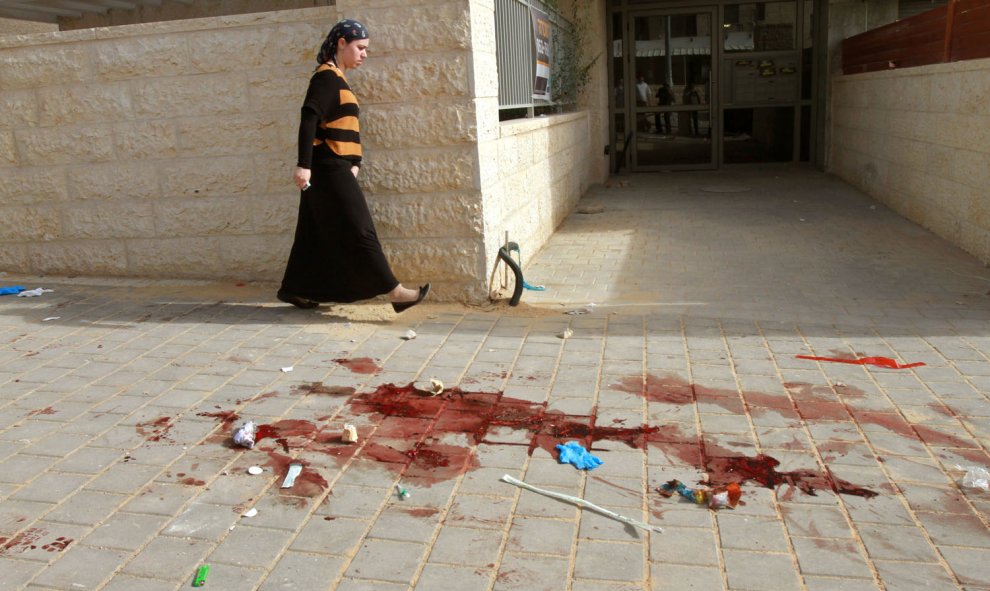 Una mujer pasa cerca de donde dos presuntos atacantes palestinos fueron abatidos a tiros por la policía israelí después de intentar subir a un autobús que transportaba niños tras apuñalar a un hombre israelí, en Beit Shemesh al oeste de Jerusalén .AFP/GIL