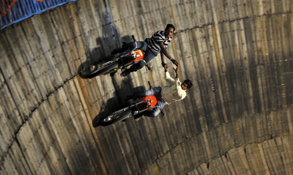 Acróbatas montan en sus motocicletas en las paredes del pozo de la muerte en una feria en las afueras de Bangalore, en la India. REUTERS