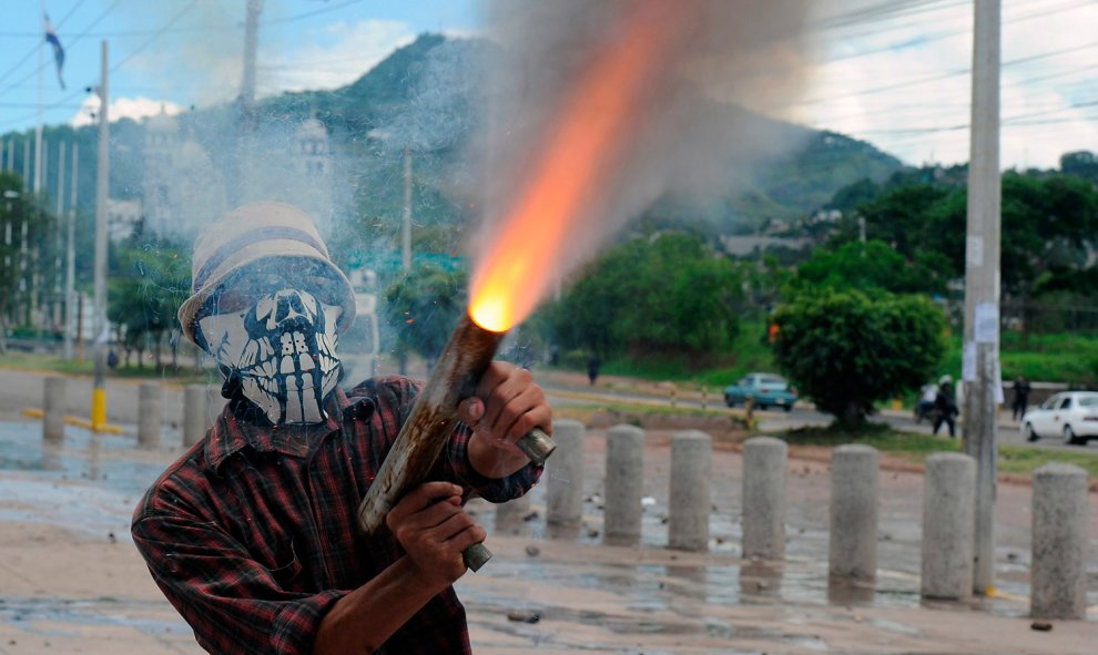 Un estudiante de la Universidad Nacional Autónoma de Honduras (UNAH) dispara un arma casera durante los enfrentamientos con la policía.- ORLANDO SIERRA (AFP)