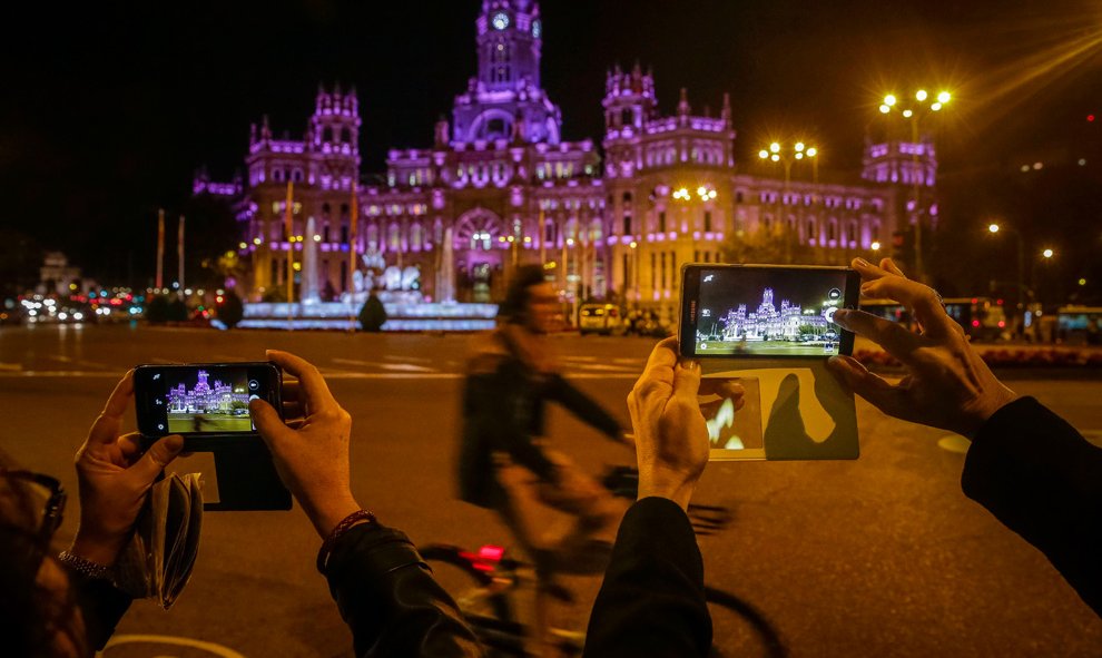 2.Varias personas fotografían la iluminación de morado del palacio de Cibeles, con motivo de la Marcha Estatal contra las Violencias Machistas. EFE/Emilio Naranjo