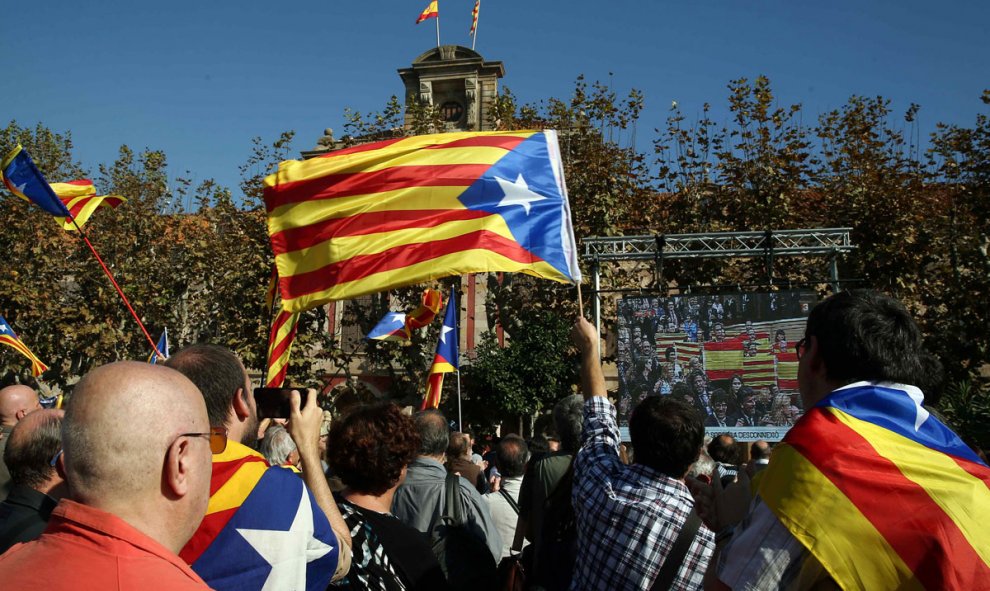 Miembros de la ANC y otras entidades soberanistas siguen, con estelades, a través de una gran pantalla instalada ante el Parlament el debate. /EFE