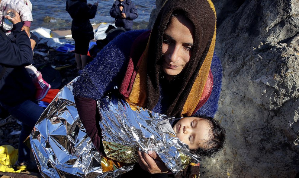 Una inmigrante afgana lleva a su bebé tras llegar en una patera a la isla griega de Lesbos. REUTERS / Yannis Behrakis