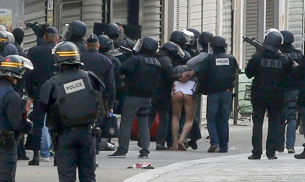 Un hombre sin pantalones es arrestado por las fuerzas espaciales de la Policía francesa durante la operación de búsqueda del terrorista fugado de los atentados de París, en Saint-Denise, Francia.- REUTERS / Jacky Naegelen