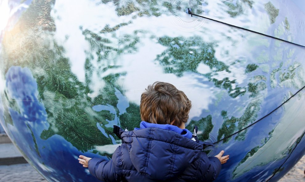 Un niño abraza un globo enorme con forma de mundo en la marcha por el clima en Roma, Italia./ REUTERS/Alessandro Bianchi