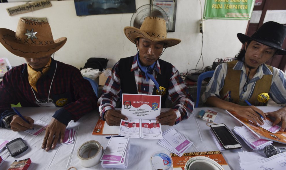 Miembros de mesa vestidos con trajes de vaquero preparan papeletas en un colegio electoral en Surabaya, en Indonesia. REUTERS