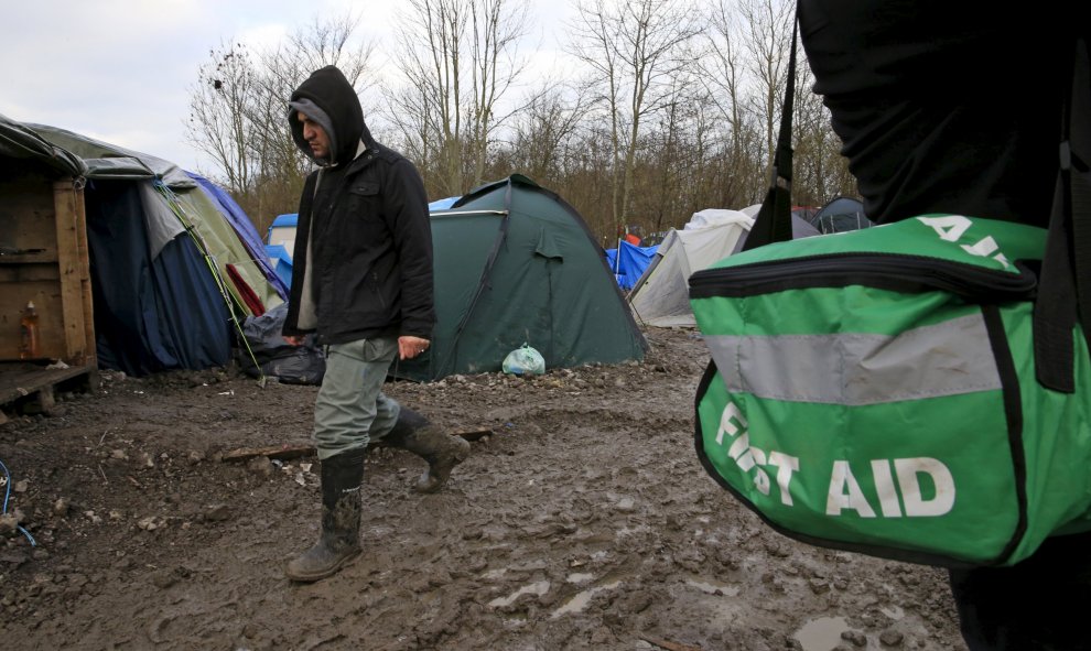 Un inmigrante pasa junto a un médico voluntario que presta servicio  en el campamento provisional para refugiados de procedentes de Irak, Kurdistán, Irán y Siria, cerca de Dunkerque (Francia). REUTERS / Pascal Rossignol