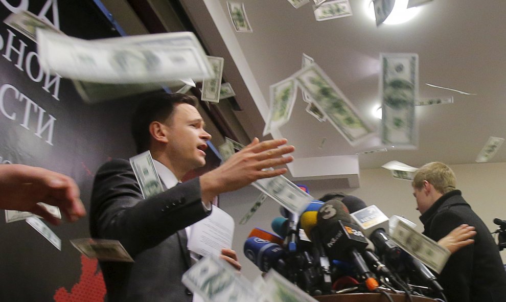 Una persona lanza trozos de papel, que simulan ser billetes, mientras el representante de la oposición rusa Ilya Yashin presenta uninforme sobre la situación actual de Chechenia, en Moscú. REUTERS/Maxim Shemetov