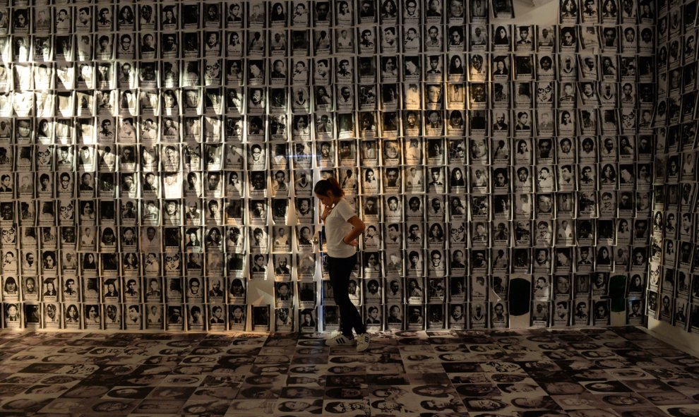 Una mujer se encuentra entre las fotos tomadas de víctimas de derechos humanos que se muestra en un museo en un campo militar en Manila el 24 de febrero de 2016. Filipinas celebra esta semana sus 30 años de democracia. AFP / TED ALJIBE