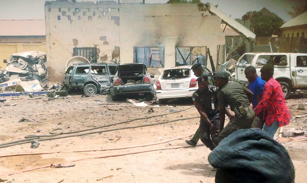 Los miembros de las fuerzas de seguridad llevan un cadáver en el sitio de una explosión que afectó a un cuartel de la policía en la ciudad de Yola, Nigeria, 25 de febrero de 2016.  REUTERS / Stringer