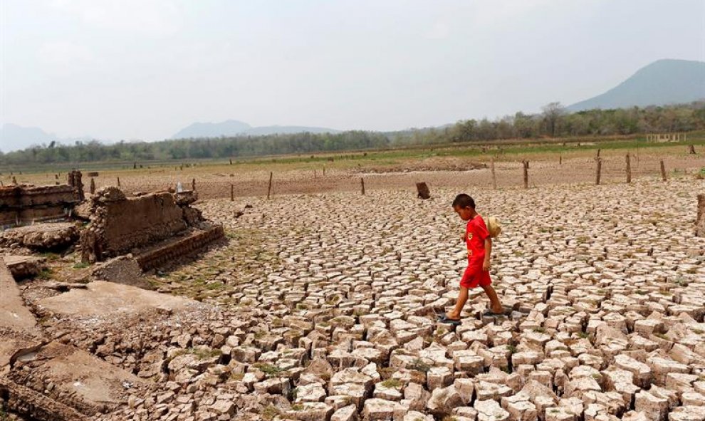 Un niño camina entre las ruinas de una aldea en una zona seca del embalse de Mae Chang en la provincia de Lampang al norte de Tailandia. EFE/Rungroj Yongrit