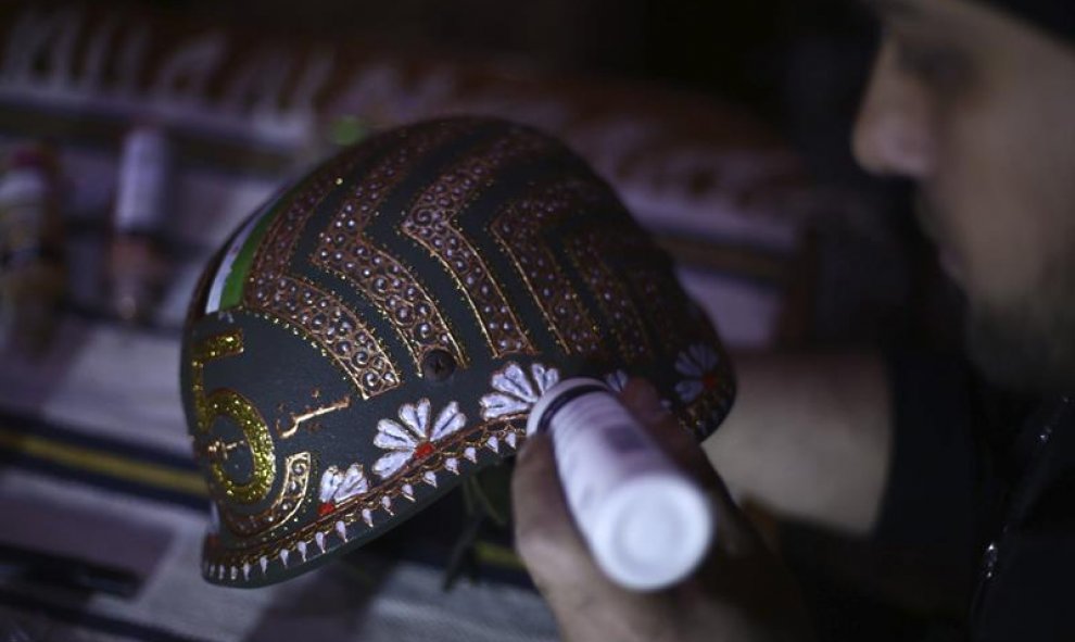 El artista sirio Akram Abo al-Foz mientras decora un casco militar en Douma, a 10 kilómetros al noreste de Damasco, Siria". EFE/Mohammed Badra