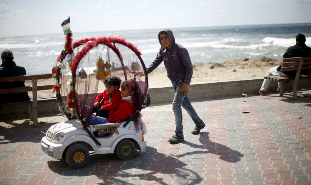 Un niño palestino de 13 años alquila su coche de juguete para que los demás pequeños puedan disfrutan de un paseo en el puerto de la ciudad de Gaza. REUTERS/Mohammed Salem