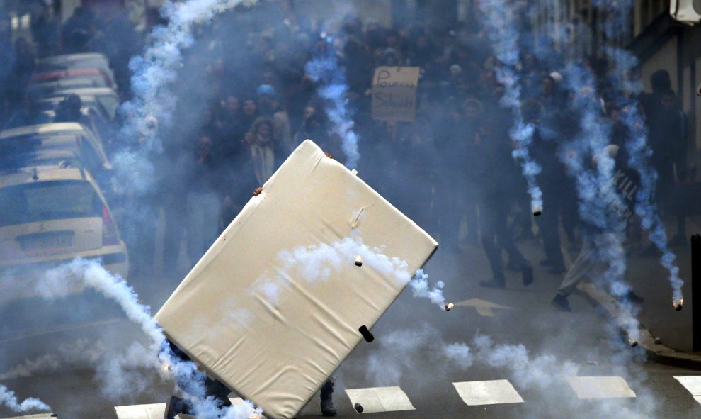 Unos jóvenes se protegen del gas lacrimógeno con un colchón durante los enfrentamientos con los antidisturbios en Nantes, Francia./ REUTERS/Stephane Mahe