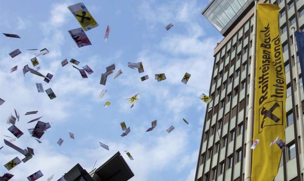 Decenas de personas lanzan falsos billetes en el aire durante una protesta contra el blanqueo de capitales, frente a la sede del banco Raiffeisen, en Viena, Austria. EFE/Christian Bruna