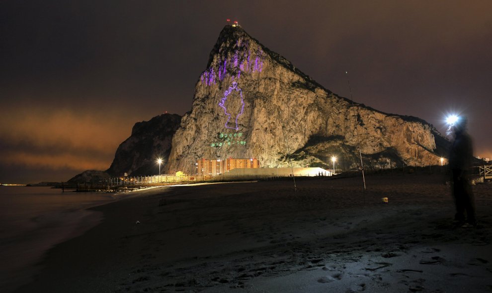 Un pescador español observa desde La Línea de la Concepción la sombra de la reina Isabel II proyectada en el Peñón de Gibraltar, con motivo de su 90 cumpleaños. REUTERS/Jon Nazca