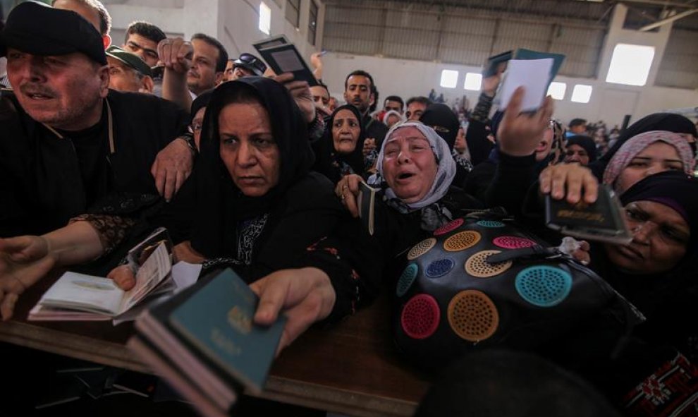 Varios palestinos muestran sus pasaportes a los policías fronterizos en el paso fronterizo de Rafah, en la franja de Gaza. EFE/Khaled Omar