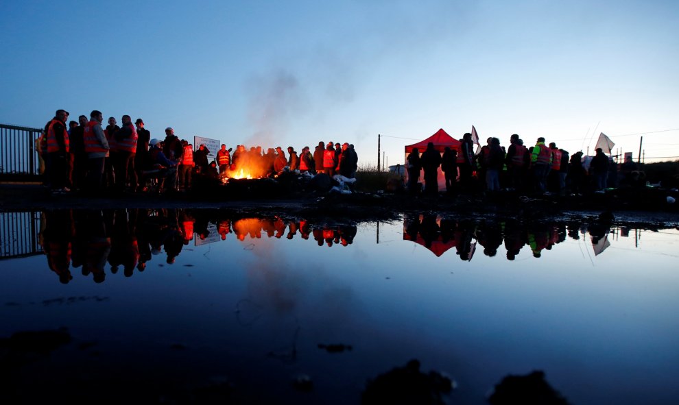 Trabajadores franceses y manifestantes junto a una barricada en llamas para bloquear la entrada del depósito de la sociedad SFDM cerca de la refinería de petróleo de Donges. REUTERS/Stephane Mahe