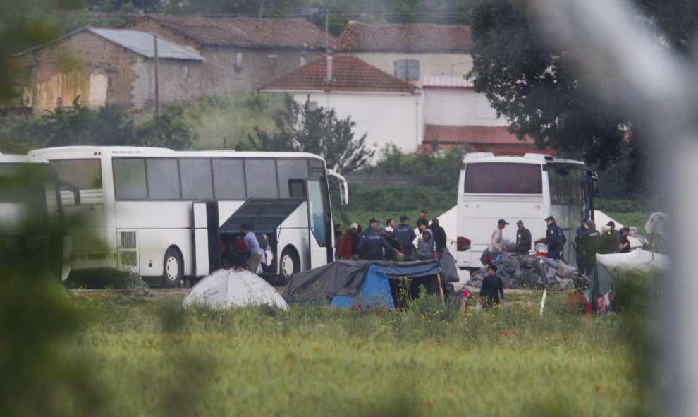 Agentes de la policía helena llevan a los refugiados a los autobuses durante el desalojo del campamento de Idomeni, en la frontera entre Grecia y Macedonia. REUTERS/OgnenTeofilovski