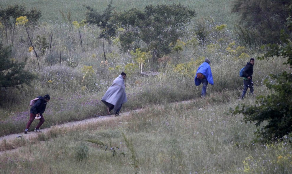 Un grupo de hombres tratan de huir campo a través para evitar ser trasladados durante el desalojo del campo de refugiados de Idomeni, en la frontega greco-macedonia. REUTERS/Alexandros Avramidis