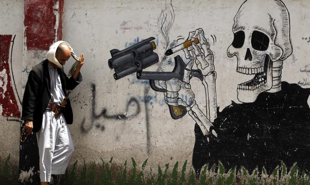 Un hombre camina junto a un grafiti antitabaco en Saná (Yemen). EFE/Yahya Arhab