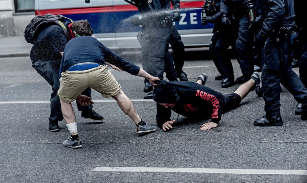 Unos manifestantes arrastran a otro ante la presencia de los antidisturbios en Viena. /EFE