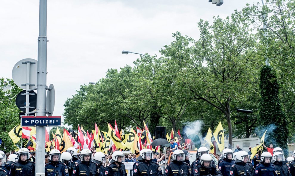 Los antidisturbios forman una fila y detrás las banderas ultras. /EFE