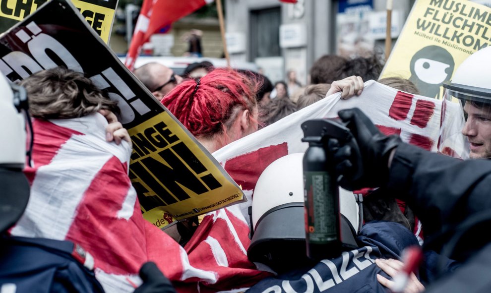 Un agente de Policía apunta con un bote de gas pimienta a varios manifestantes en Viena. /EFE