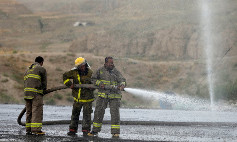 Bomberos afganos lavan la carretera en el sitio de un ataque suicida al oeste de Kabul, Afganistán.- REUTERS / Mohammad Ismail