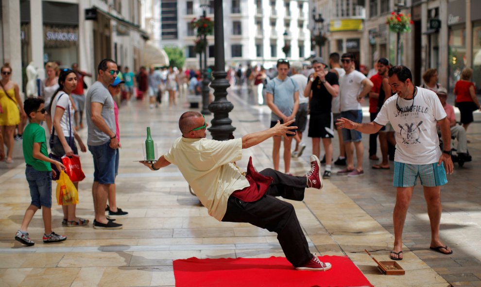 Un artista callejero disfrazado de camarero actúa en una calle de Málaga.  REUTERS/Jon Nazca.