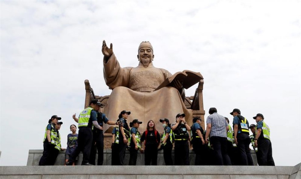 Varios policías surcoreanos detienen a miembros de un sindicato de trabajadores a tiempo parcial durante una protesta contra la política laboral del Gobierno en una calle principal de Seúl, Corea del Sur. EFE/Jung Byung-Hyuk.