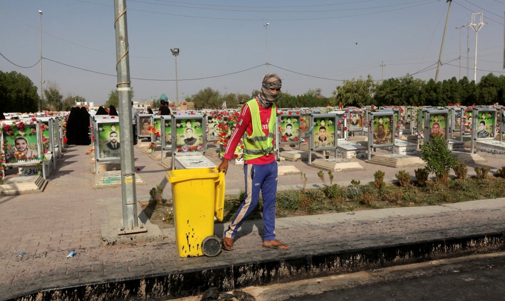 Un trabajador municipal con un contenedor de basura en el cementerio de Wadi al-Salam (que en árabe significa 'Valle de la Paz'), en Nayaf, al sur de Bagdad. REUTERS / Alaa Al-Marjani