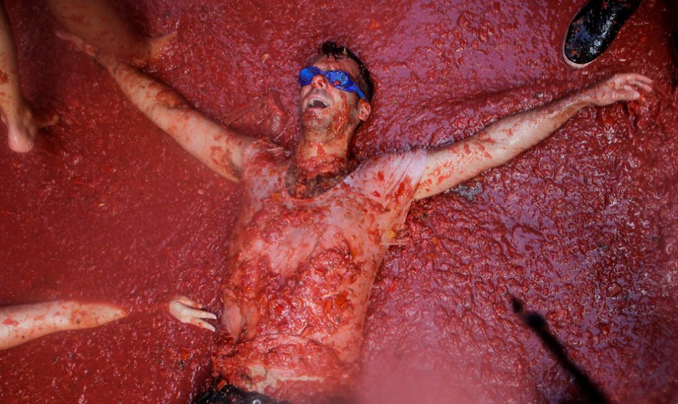 Uno de los participantes en la Tomatina de Buñol, tumbado sobre la pulpa de tomate en la calle. REUTERS / Heino Kalis