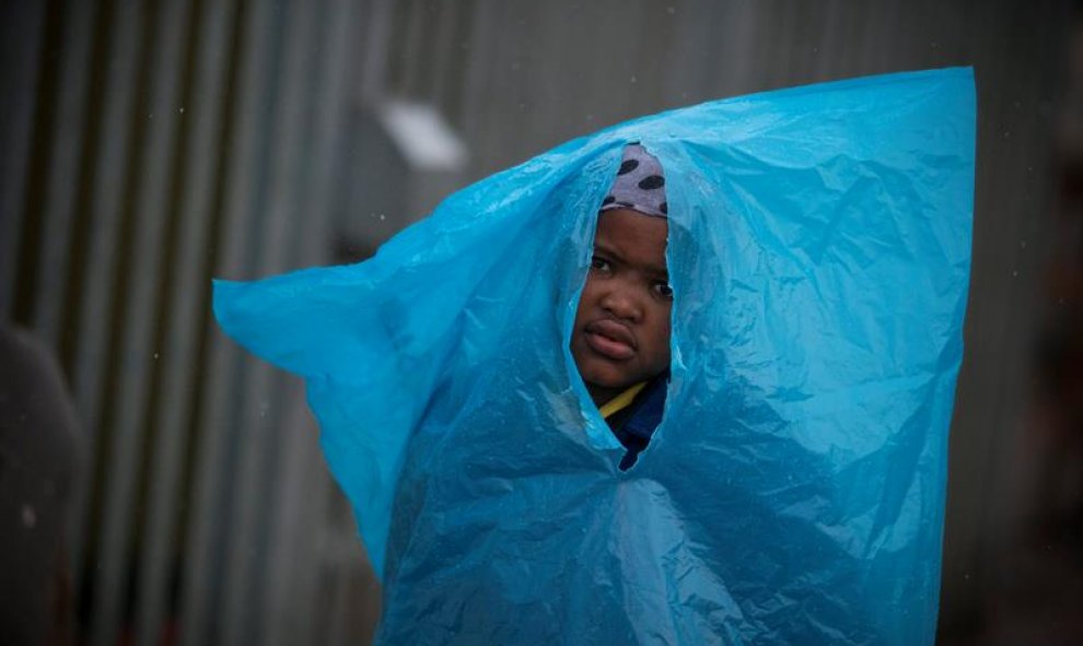 Un niño sudafricano camina protegido con una bolsa de plástico durante una tormenta en Ciudad del Cabo, Sudáfrica. EFE/Nic Bothma