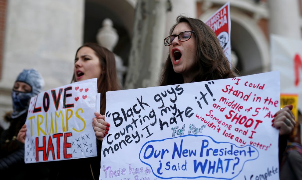 Dos chicas con pancartas contra Trump en la manifestación en Madrid / REUTERS