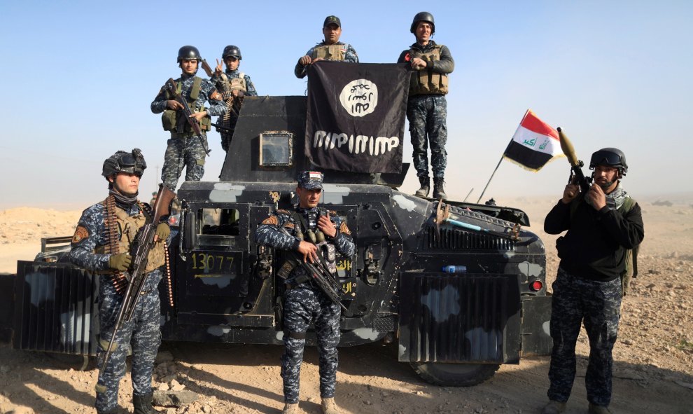 Miembros de la policía federal posan con la bandera del Estado islámico a lo largo de una calle de Albu Saif, al sur de Mosul, Irak. REUTERS/Zohra Bensemra