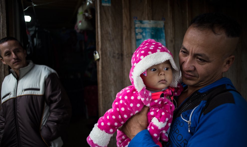 Un guerrillero sostiene en brazo a su hija de pocos meses en el campamento para desmovilizados de las FARC en La Fila, región de Tolima.-JAIRO VARGAS