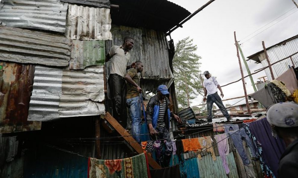 Simpatizantes del líder opositor Raila Odinga subidos al tejado de una casa poniéndose a salvo del fuego.EFE/Daniel Irungu