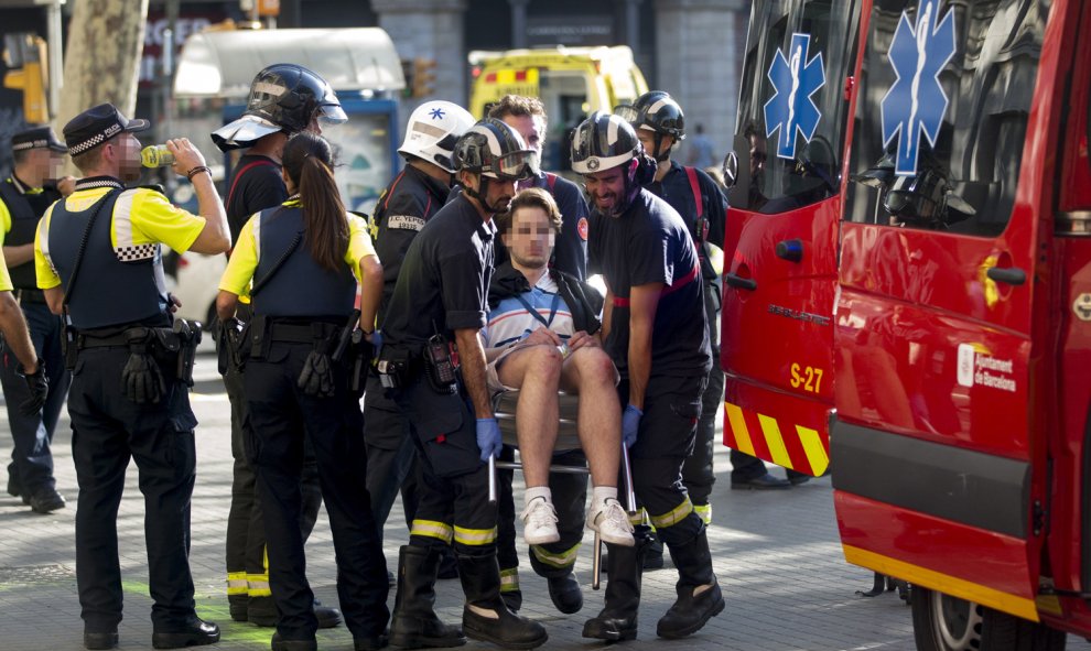 Los bomberos atienden a uno de los heridos en el atentado de Barcelona.- EFE