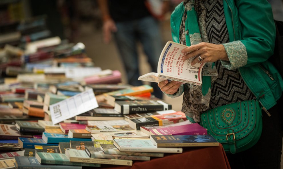 Una mujer hojea un libro en una de las paradas de las Ramblas de Barcelona durante la diada de Sant Jordi