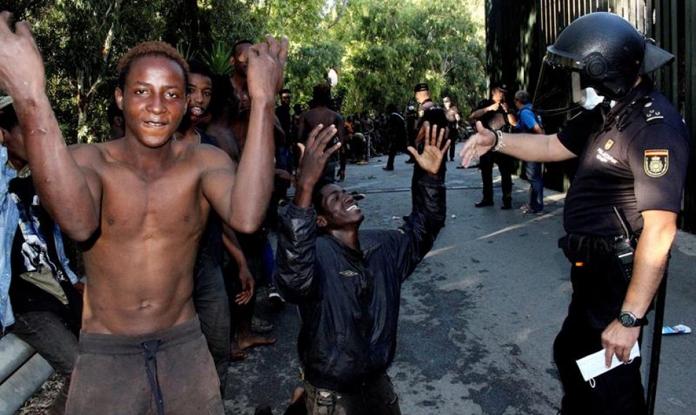 Los migrantes frente al cuerpo de la Policía Nacional/EFE