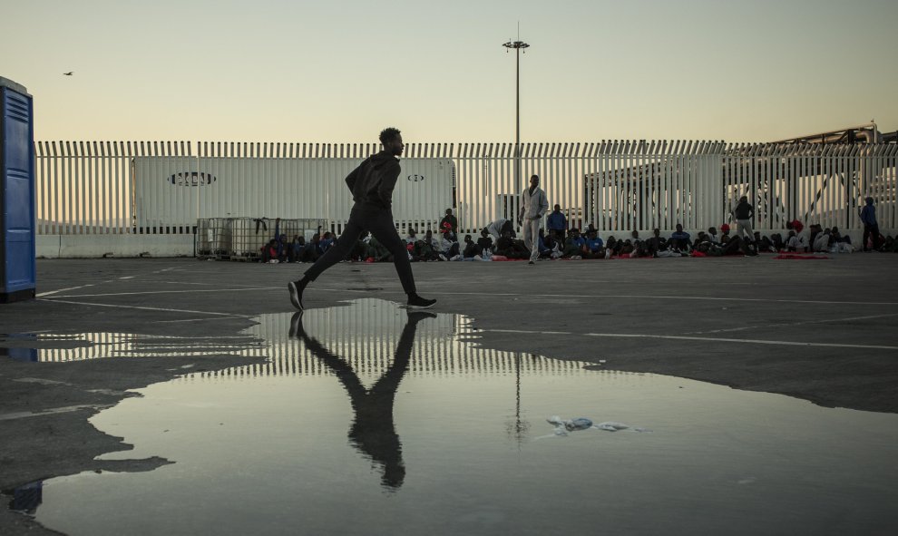 Un joven esquiva un charco de los urinarios portátles instalados en el puerto de Algeciras, donde están retenidos cientos de mitgrantes rescatads en pateras durante el finde semana. JAIRO VARGAS