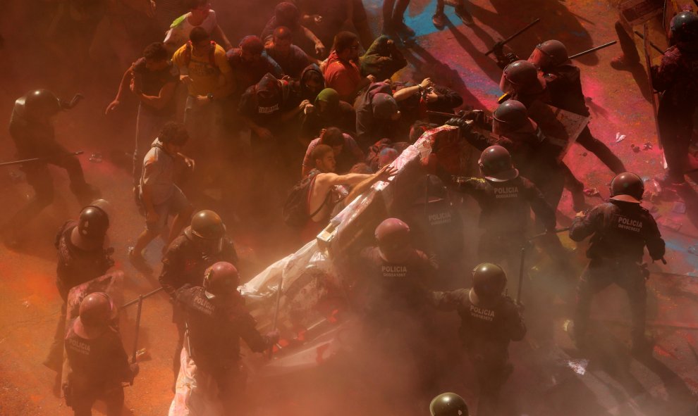 Los mossos acorralan a varios manifestantes parapetados en un material acolchado para disminuir el daño de los porrazos. | Jon Nazca / Reuters